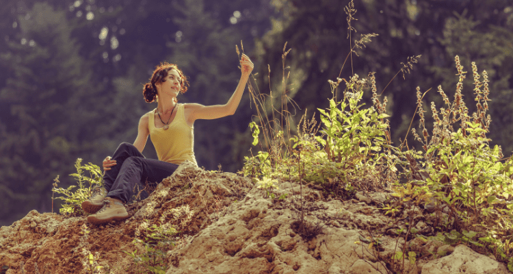 Woman enjoying all of the small details of nature around her on her hike