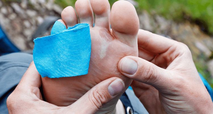 Hiker using tape as padding on her feet to prevent blisters
