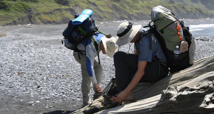 Hikers inspecting their feet during a long hike on The Lost Coast