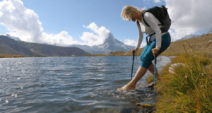 Woman removing her hiking shoes to cross water