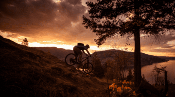 Mountain Biker riding downhill during sunset overlooking a lake