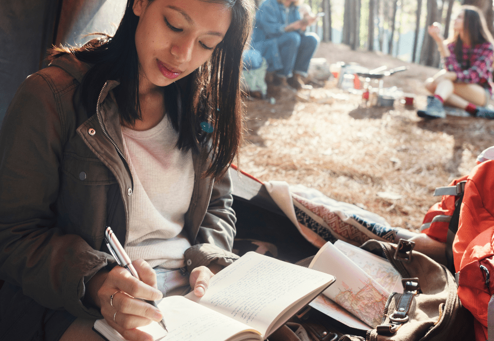 Woman adventure journaling in their campsite